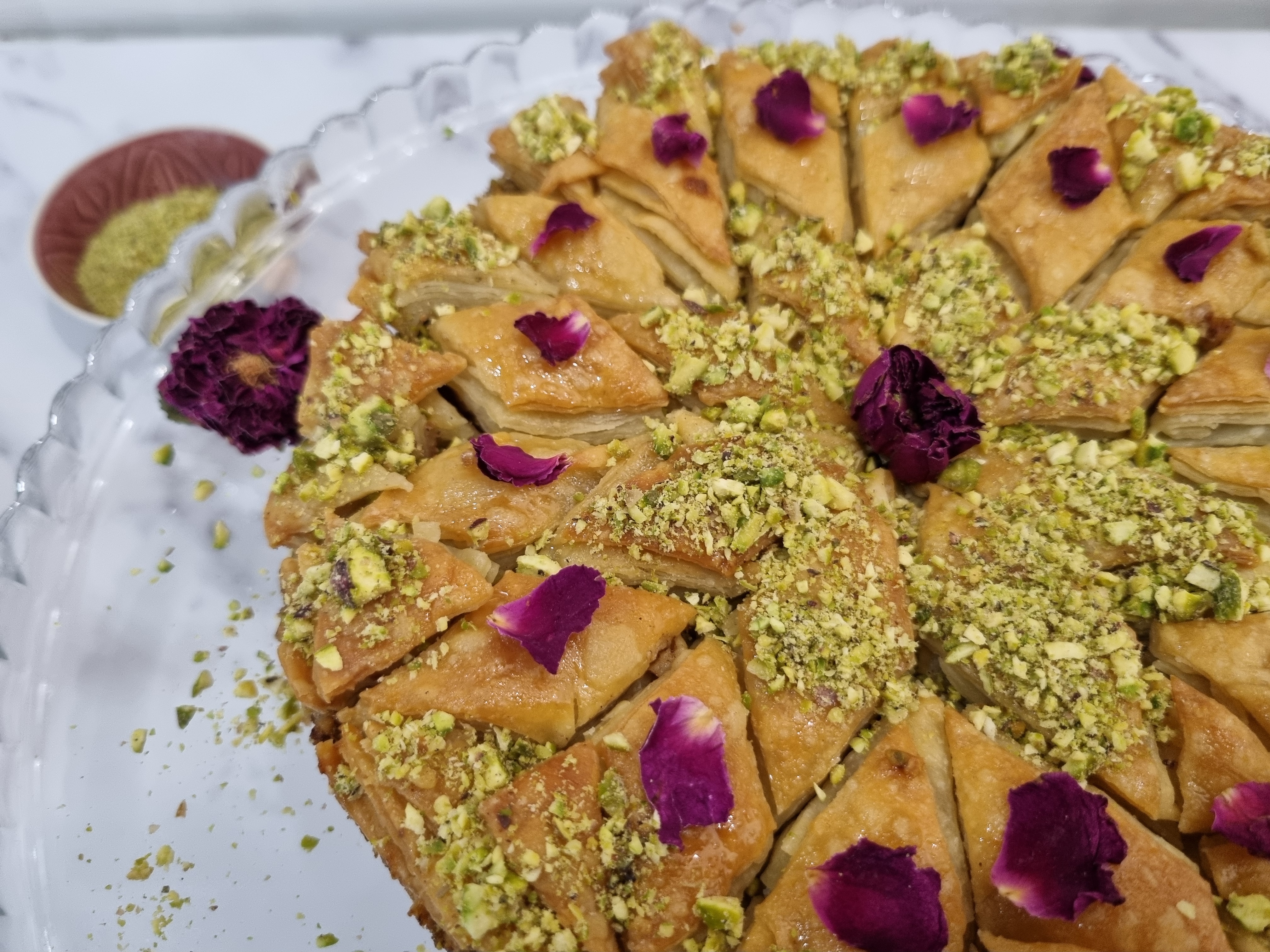 Close up of homemade baklava decorated with pistachios and rose petals